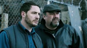 Bob (Tom Hardy) with his boss and cousin, Marv (James Gandolfini, in his final role before his death) outside the back of Cousin Marv's, listening to their Chechen gangster boss.