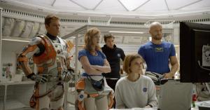 Mark Watney (Matt Damon) with the NASA crew, led by Melissa Lewis (Jessica Chastain, sitting down), before they go out to explore.