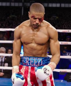 Adonis Creed in the ring, still standing, despite having taken a battering from his opponent.